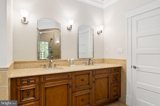 bathroom with vanity, a shower with shower door, crown molding, and tile walls