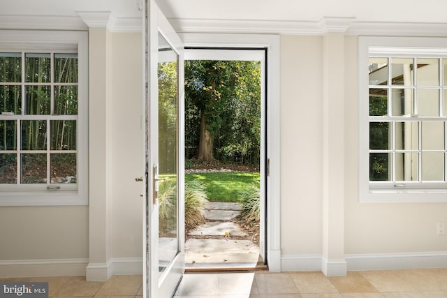 entryway with a wealth of natural light, light tile patterned flooring, and ornamental molding