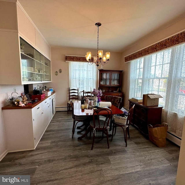 dining area with an inviting chandelier, a baseboard heating unit, and dark wood-type flooring