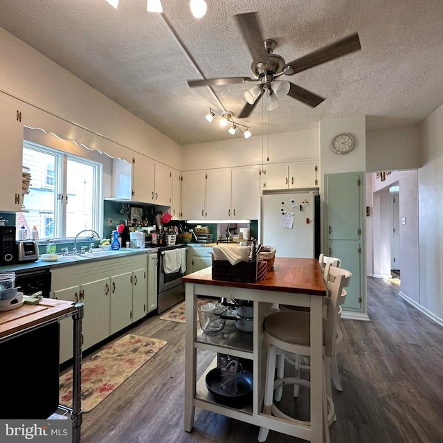 kitchen with electric stove, white refrigerator, a textured ceiling, white cabinets, and dark hardwood / wood-style flooring