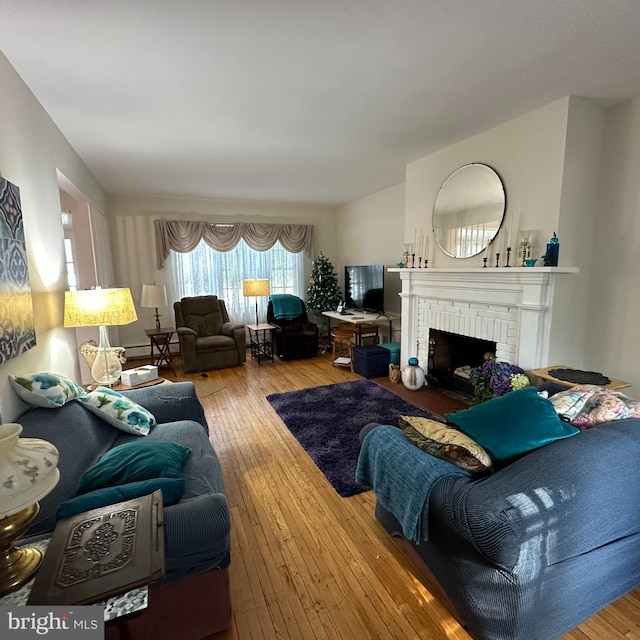 living room with a brick fireplace and hardwood / wood-style flooring