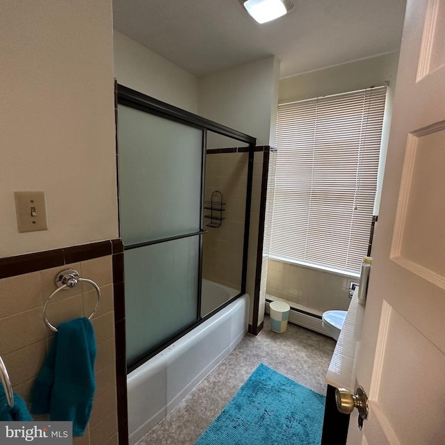 bathroom featuring tile walls, shower / bath combination with glass door, and toilet