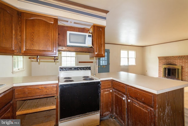 kitchen with white appliances, kitchen peninsula, and a fireplace