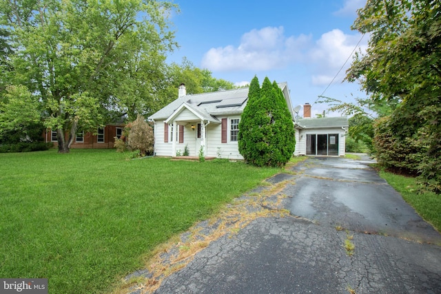 view of front of home with solar panels and a front lawn