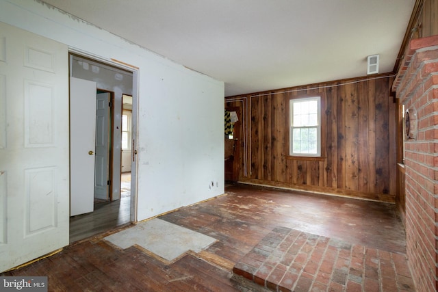 unfurnished room with wood walls, dark hardwood / wood-style flooring, and brick wall