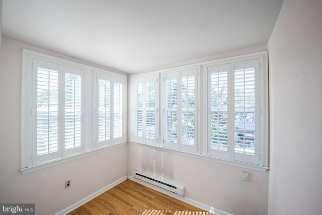 unfurnished room featuring light wood-type flooring and baseboard heating