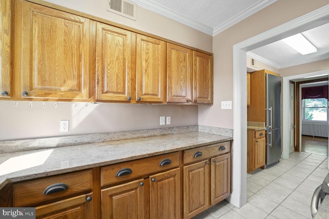 kitchen with light tile patterned floors, high quality fridge, ornamental molding, a textured ceiling, and light stone countertops