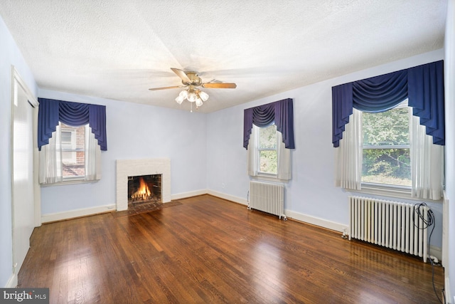 unfurnished living room with a wealth of natural light, radiator, and dark hardwood / wood-style floors