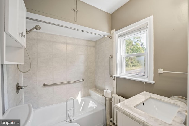 full bathroom featuring tiled shower / bath, vanity, radiator, and toilet