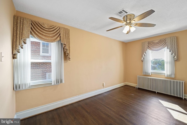 spare room with a textured ceiling, radiator heating unit, and dark hardwood / wood-style flooring