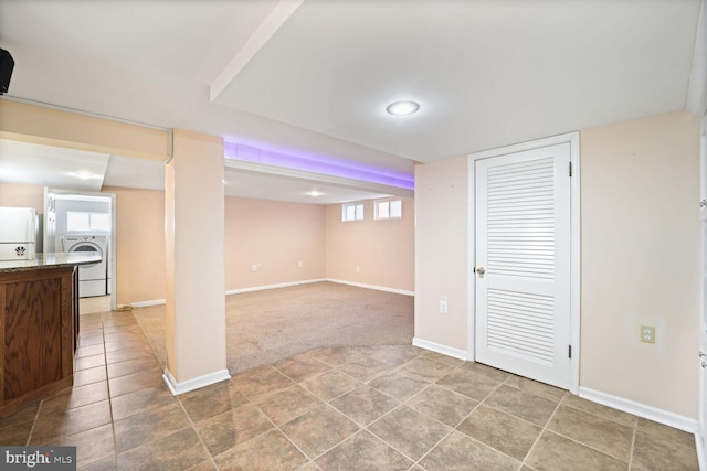 basement featuring washer / dryer, white refrigerator, and carpet floors