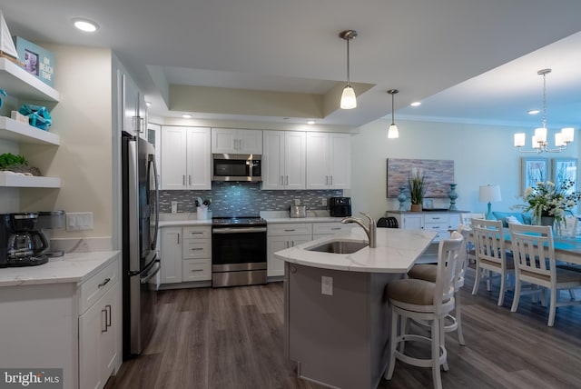 kitchen featuring appliances with stainless steel finishes, white cabinets, light stone countertops, dark hardwood / wood-style flooring, and sink