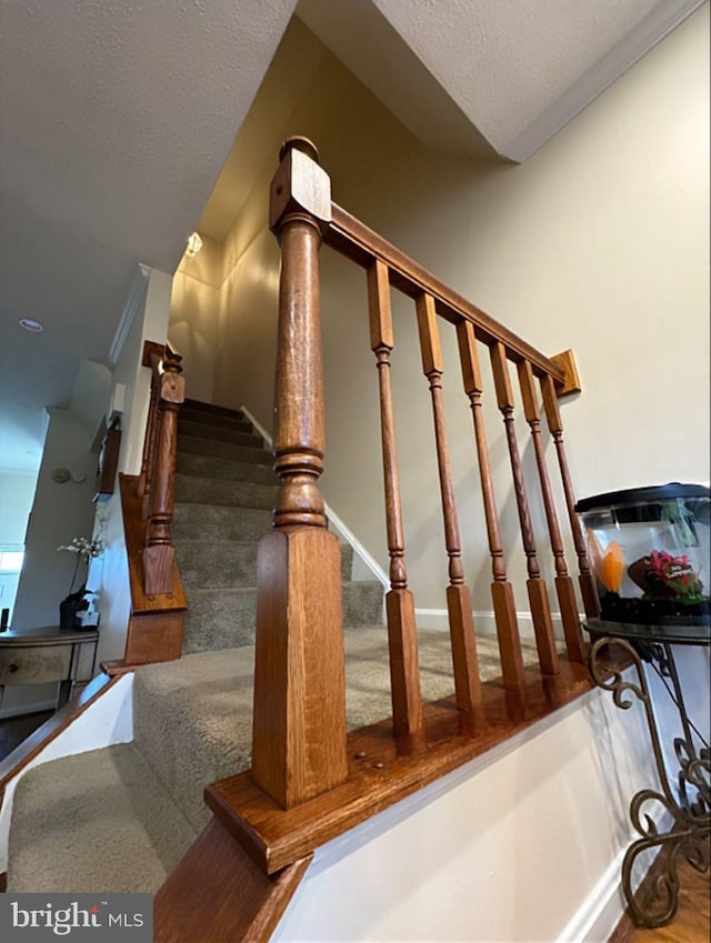 stairs featuring a textured ceiling and ornamental molding