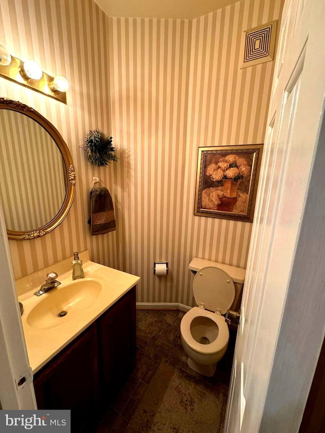 bathroom with toilet, vanity, and tile patterned flooring