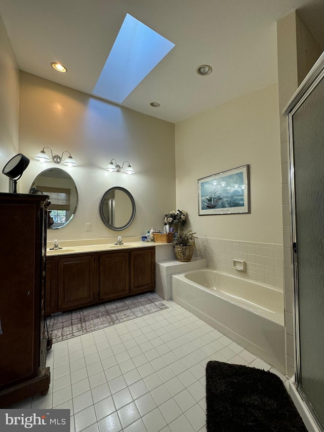 bathroom featuring vanity, tile patterned flooring, a bathtub, and a skylight