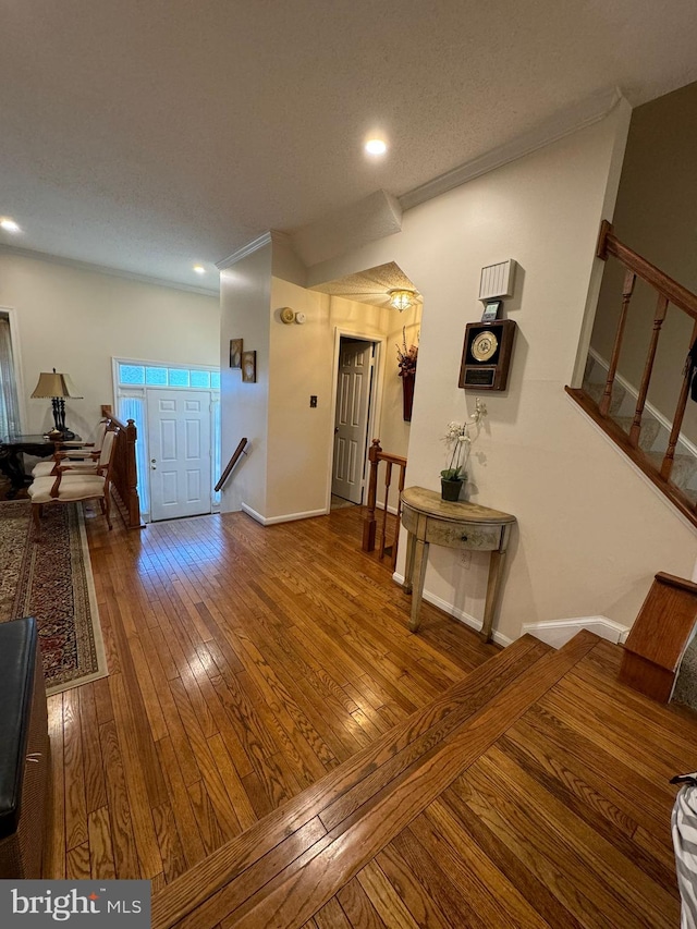 foyer featuring ornamental molding, wood-type flooring, and a textured ceiling