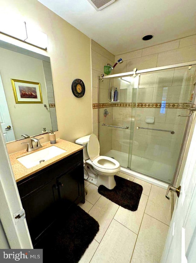 bathroom featuring walk in shower, vanity, toilet, and tile patterned flooring