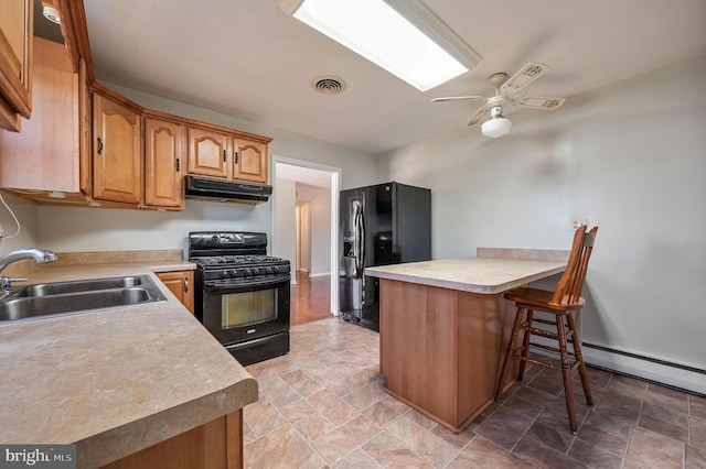 kitchen featuring a breakfast bar, black appliances, sink, ceiling fan, and kitchen peninsula