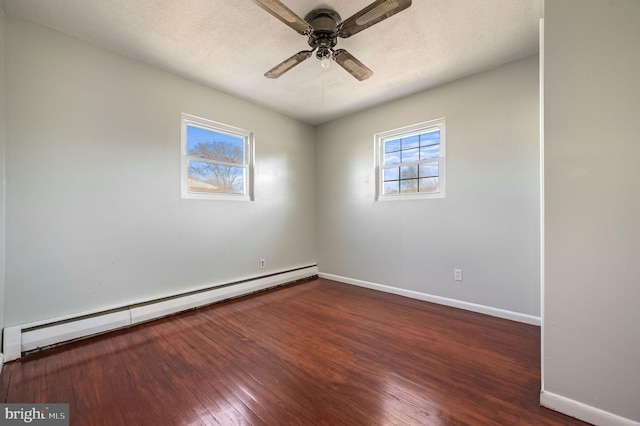 spare room with ceiling fan, baseboard heating, and dark wood-type flooring