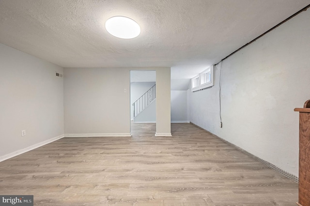 basement featuring a textured ceiling and light wood-type flooring