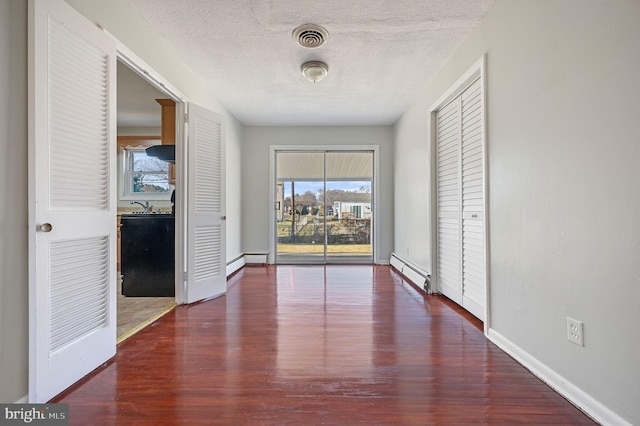 hallway with a textured ceiling, dark hardwood / wood-style flooring, and baseboard heating