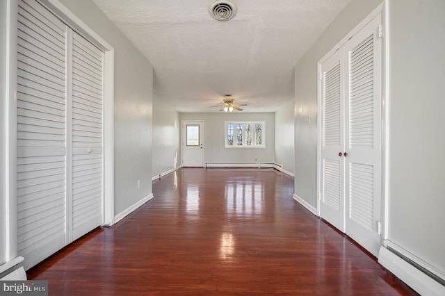 hall featuring dark wood-type flooring, a textured ceiling, and a baseboard heating unit