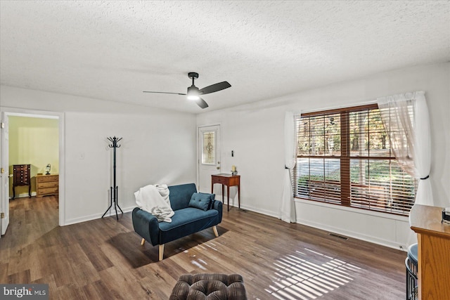 sitting room with dark wood-type flooring, a textured ceiling, and ceiling fan