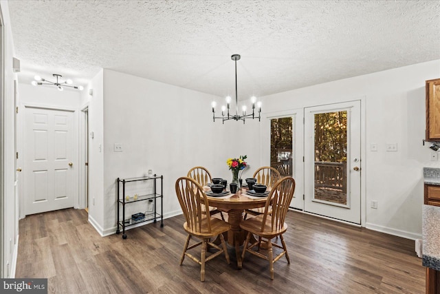 dining room with dark wood-type flooring, a notable chandelier, and a textured ceiling