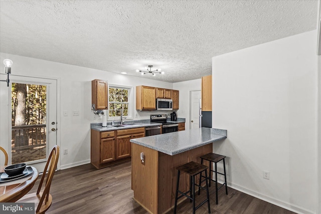 kitchen with appliances with stainless steel finishes, kitchen peninsula, dark hardwood / wood-style flooring, and a breakfast bar area