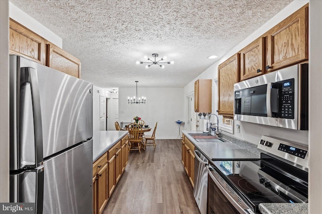 kitchen featuring hardwood / wood-style flooring, sink, a notable chandelier, decorative light fixtures, and appliances with stainless steel finishes