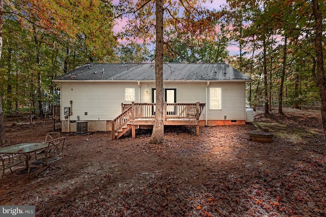 back house at dusk featuring a wooden deck and central AC unit