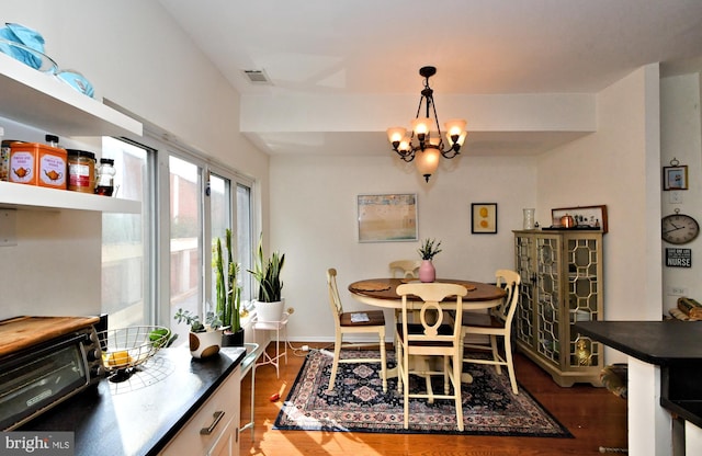 dining area with dark wood-type flooring and an inviting chandelier