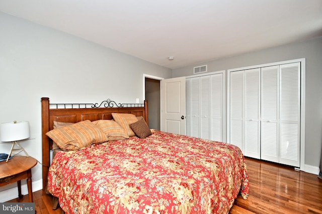 bedroom with two closets and hardwood / wood-style floors