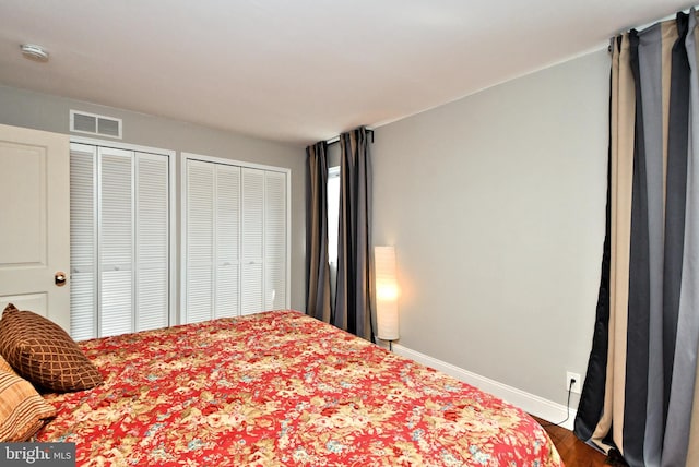 bedroom featuring hardwood / wood-style floors and multiple closets