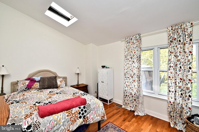 bedroom featuring vaulted ceiling with skylight and wood-type flooring