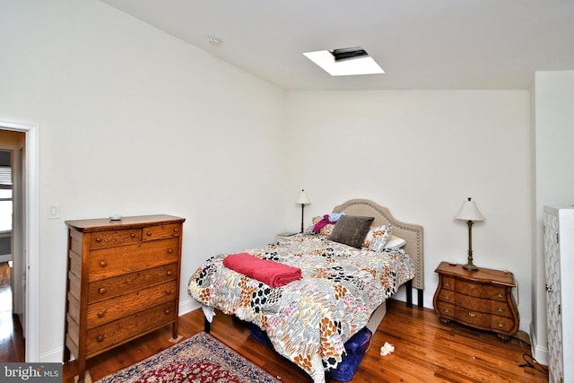 bedroom with hardwood / wood-style flooring and lofted ceiling with skylight