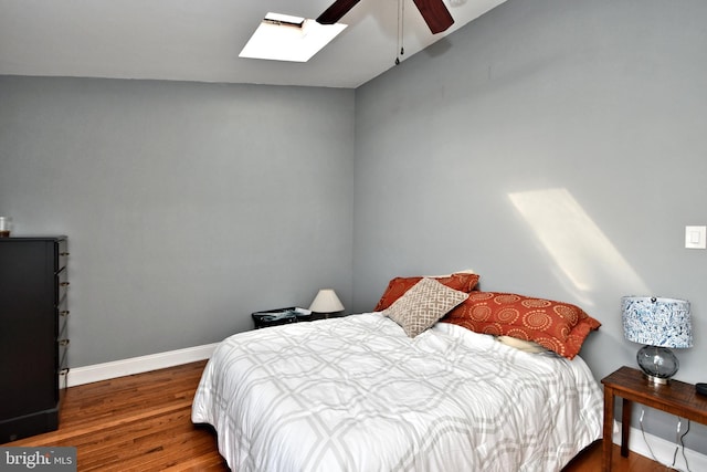 bedroom featuring ceiling fan, dark wood-type flooring, and vaulted ceiling with skylight