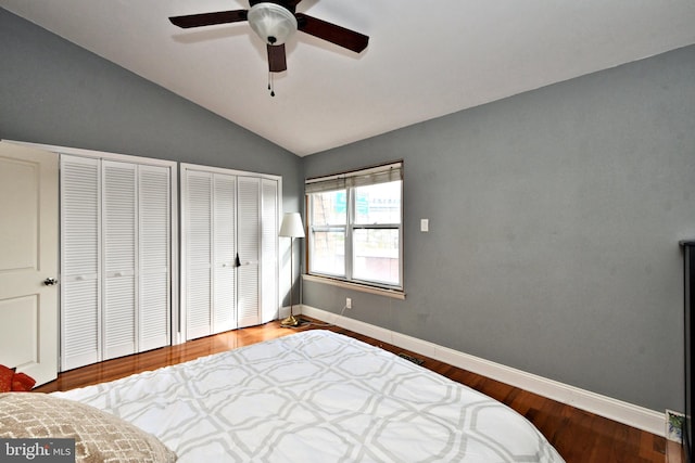 bedroom featuring multiple closets, vaulted ceiling, hardwood / wood-style flooring, and ceiling fan