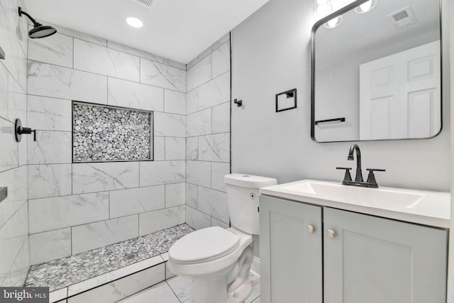 bathroom with vanity, toilet, and tiled shower