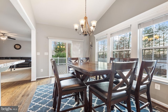 dining area with lofted ceiling, ceiling fan with notable chandelier, light hardwood / wood-style floors, and a healthy amount of sunlight