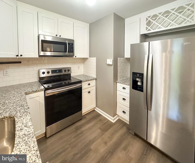 kitchen featuring light stone countertops, stainless steel appliances, tasteful backsplash, white cabinets, and dark wood-type flooring