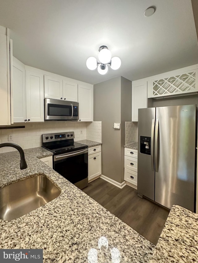 kitchen with light stone counters, white cabinets, stainless steel appliances, and sink