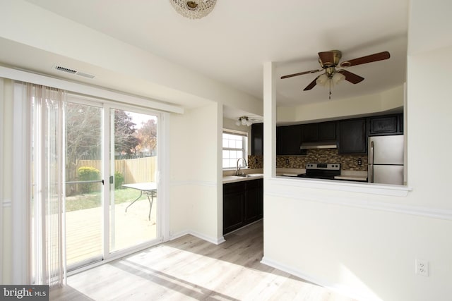 kitchen with a wealth of natural light, decorative backsplash, light hardwood / wood-style flooring, and appliances with stainless steel finishes