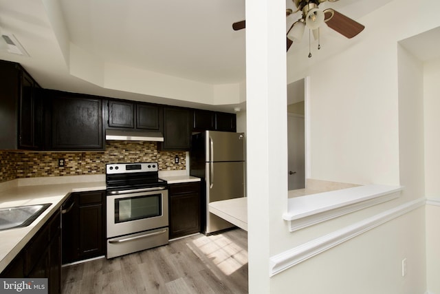 kitchen featuring stainless steel appliances, decorative backsplash, sink, ceiling fan, and light wood-type flooring