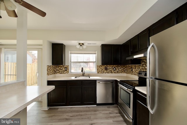 kitchen with tasteful backsplash, appliances with stainless steel finishes, sink, ceiling fan, and light hardwood / wood-style flooring