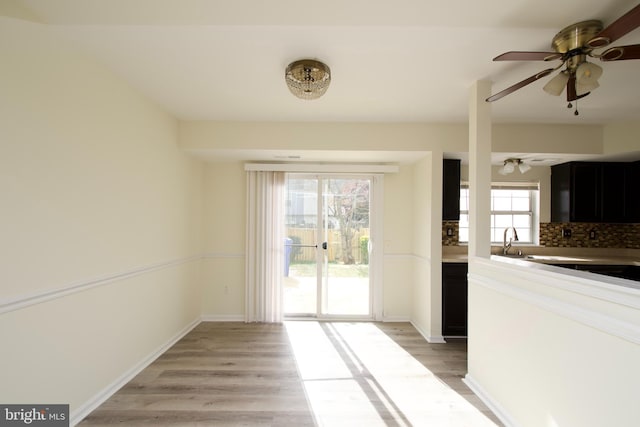 interior space with light hardwood / wood-style floors, ceiling fan, plenty of natural light, and decorative backsplash