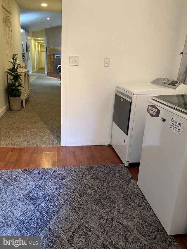 clothes washing area with dark hardwood / wood-style flooring and washer and dryer