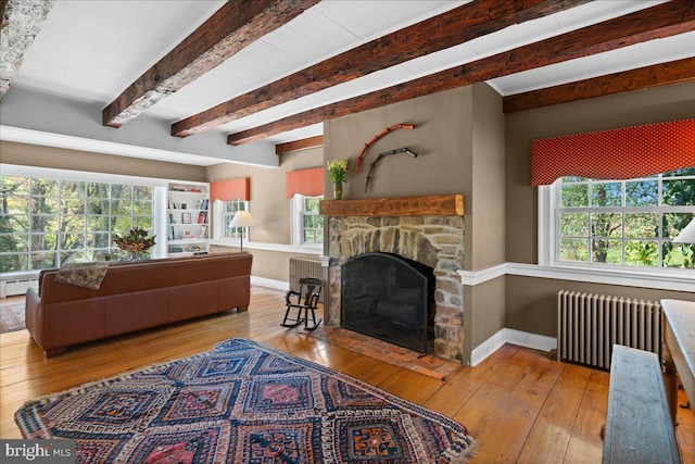 living room with beam ceiling, hardwood / wood-style flooring, radiator heating unit, and a fireplace