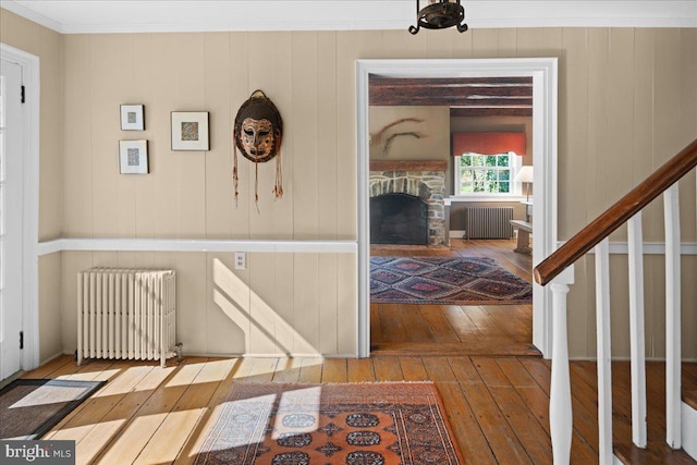 corridor with crown molding, wood-type flooring, and radiator heating unit