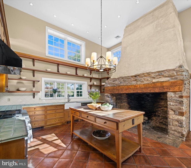 kitchen featuring decorative backsplash, sink, decorative light fixtures, an inviting chandelier, and a fireplace